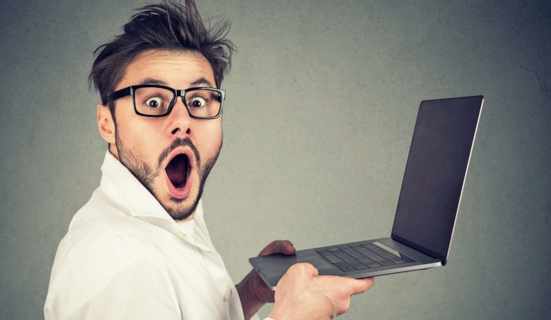 Astonished man holding laptop