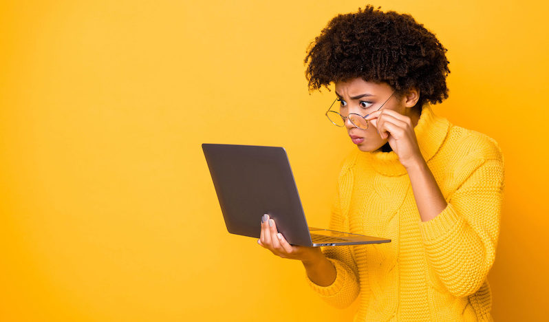 Copyspace photo of charming cute nice pensive girlfriend trendy stylish wearing yellow knitted jumper holding laptop with her hand staring onto screen afraid isolated vivid color background